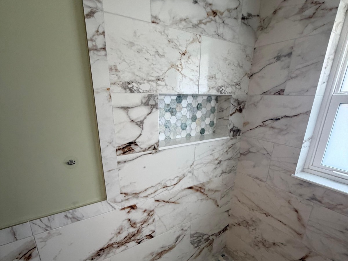 Calacatta marble shower with a hexagon mosaic floor