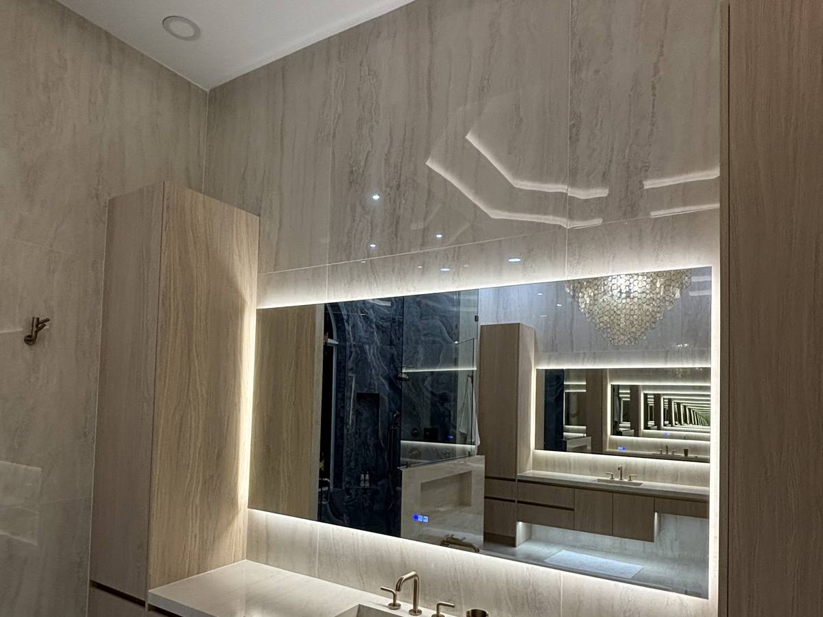 Bathroom vanity wall with backlit mirror and custom cabinetry
